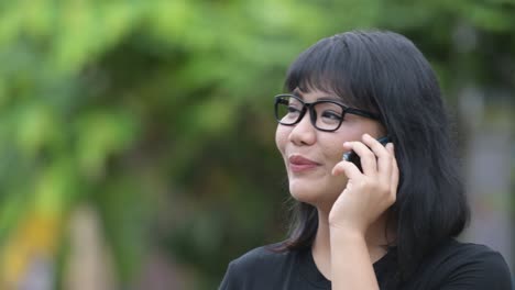 beautiful happy asian businesswoman talking on phone in the streets outdoors