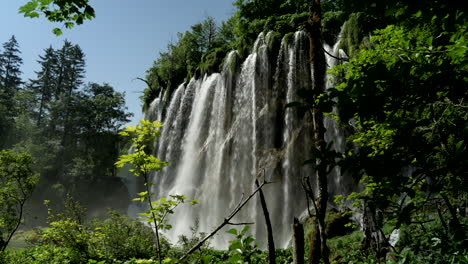 big waterfall hidden behind the leaves of the trees