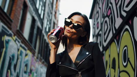 stylish woman drinking soda in urban setting