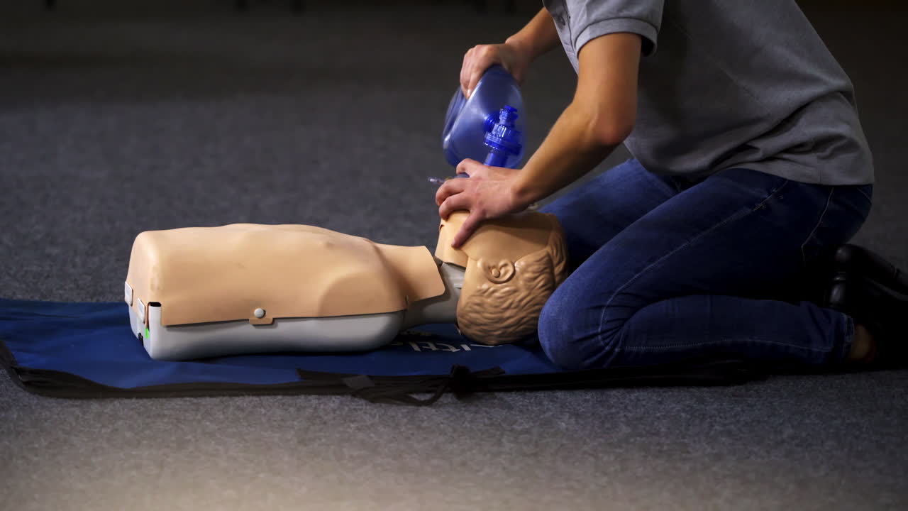 Instructor demonstrates breathing exercise on a mannequin. Woman on a mat on the floor over the dummy giving a medical training.