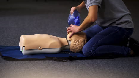 instructor demonstrates breathing exercise on a mannequin. woman on a mat on the floor over the dummy giving a medical training.