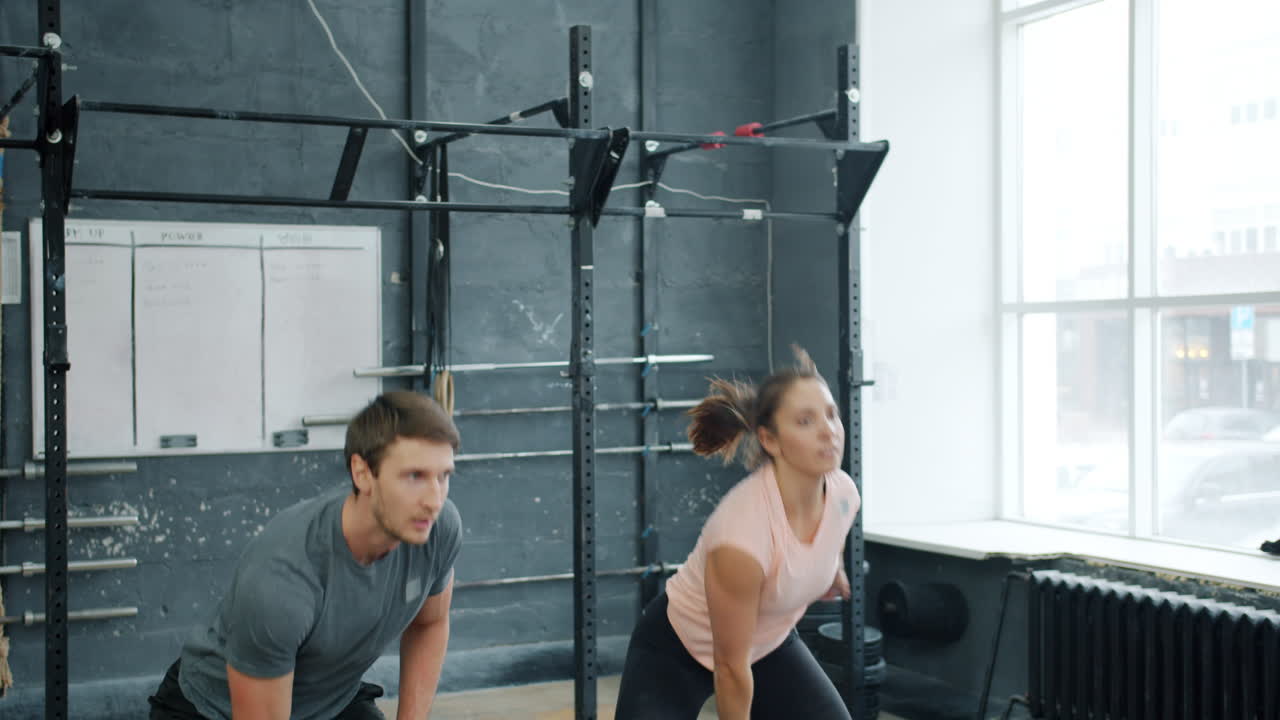 Couple Working Out with Kettlebells in Gym