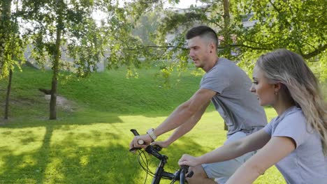 una pareja en bicicleta en un parque.