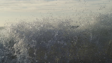 glassy sunrise wave crashes gently on smooth shore, golden reflections shimmer in slow motion