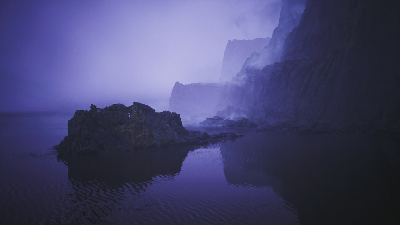 Costa tranquilla con nebbia che si alza su acque riflettenti e rocce.