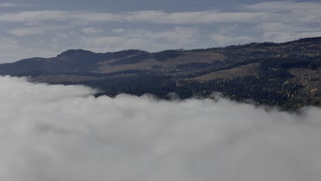 Serenidad-Hacia-El-Cielo:-Captura-Aérea-De-Montañas-Cubiertas-De-Nubes-Cerca-De-Un-Pequeño-Fuerte