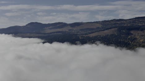 serenidad hacia el cielo: captura aérea de montañas a la deriva de nubes cerca de little fort