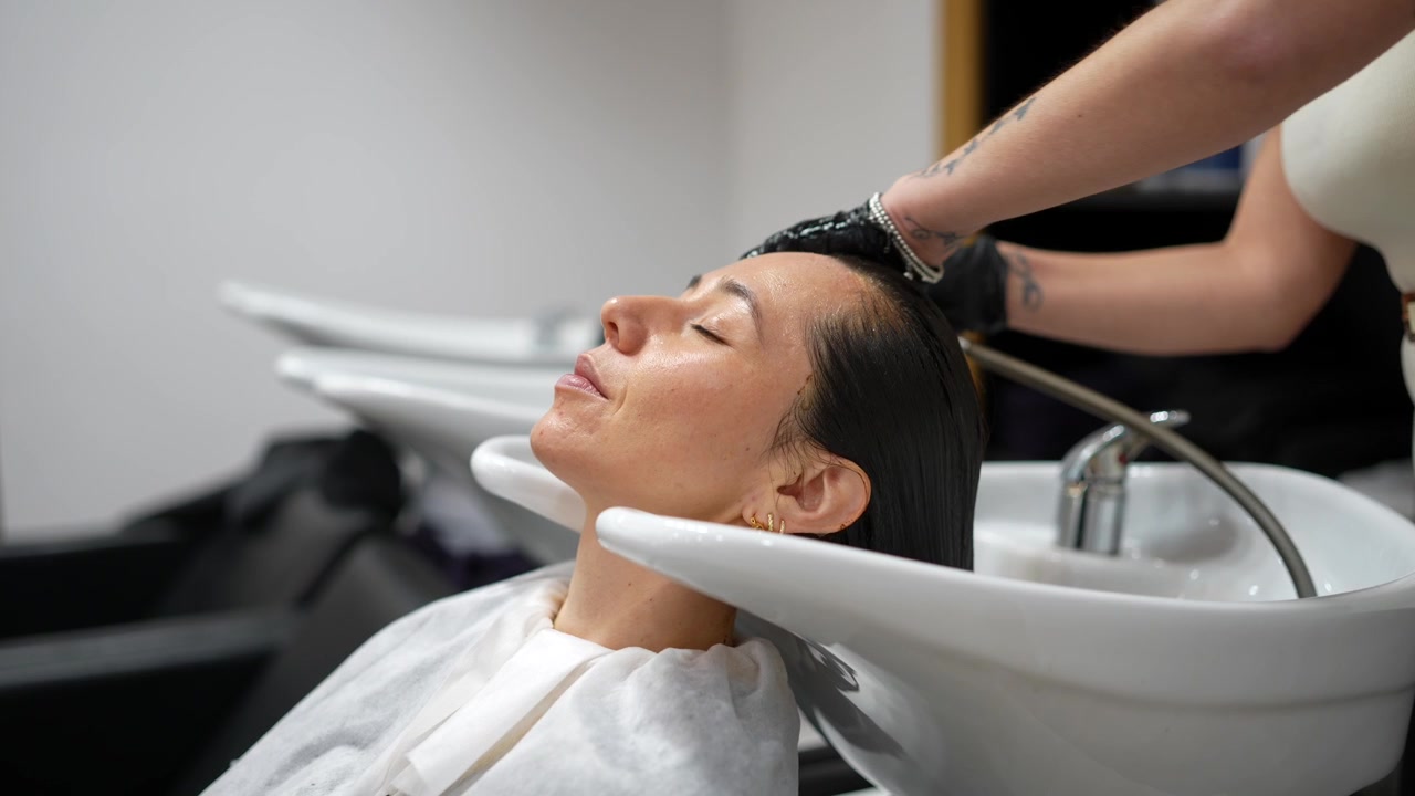 Parrucchiere che lava i capelli al cliente in un salone professionale