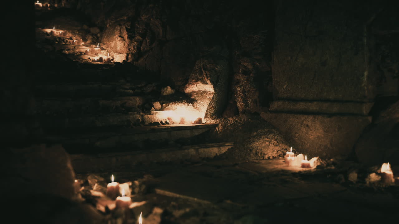 Flickering candle lights illuminate stone steps in a dark setting