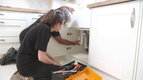 fontanero mostrando a una aprendiz femenina cómo instalar un fregadero de cocina