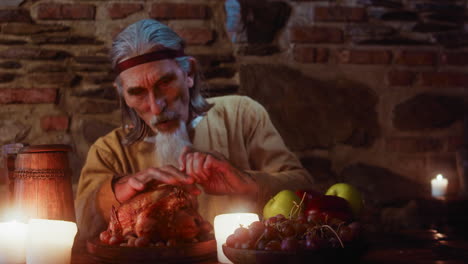 el señor mayor se sienta y come en la taberna. el hambriento noble de cabello gris disfruta de una rica comida en el castillo del rey. el anciano con barba de cabra visita el banquete en la fiesta