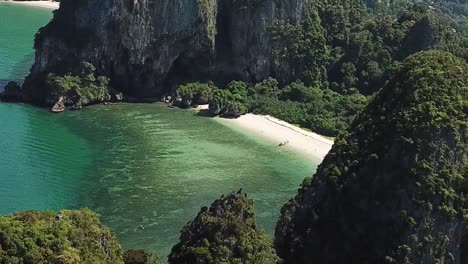 Tropical-Lagoon-and-White-Sand-Beach-Hidden-Between-Sea-Cliffs,-Pull-Back-Aerial