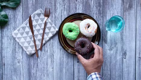 hand reaching for a doughnut on a wooden table