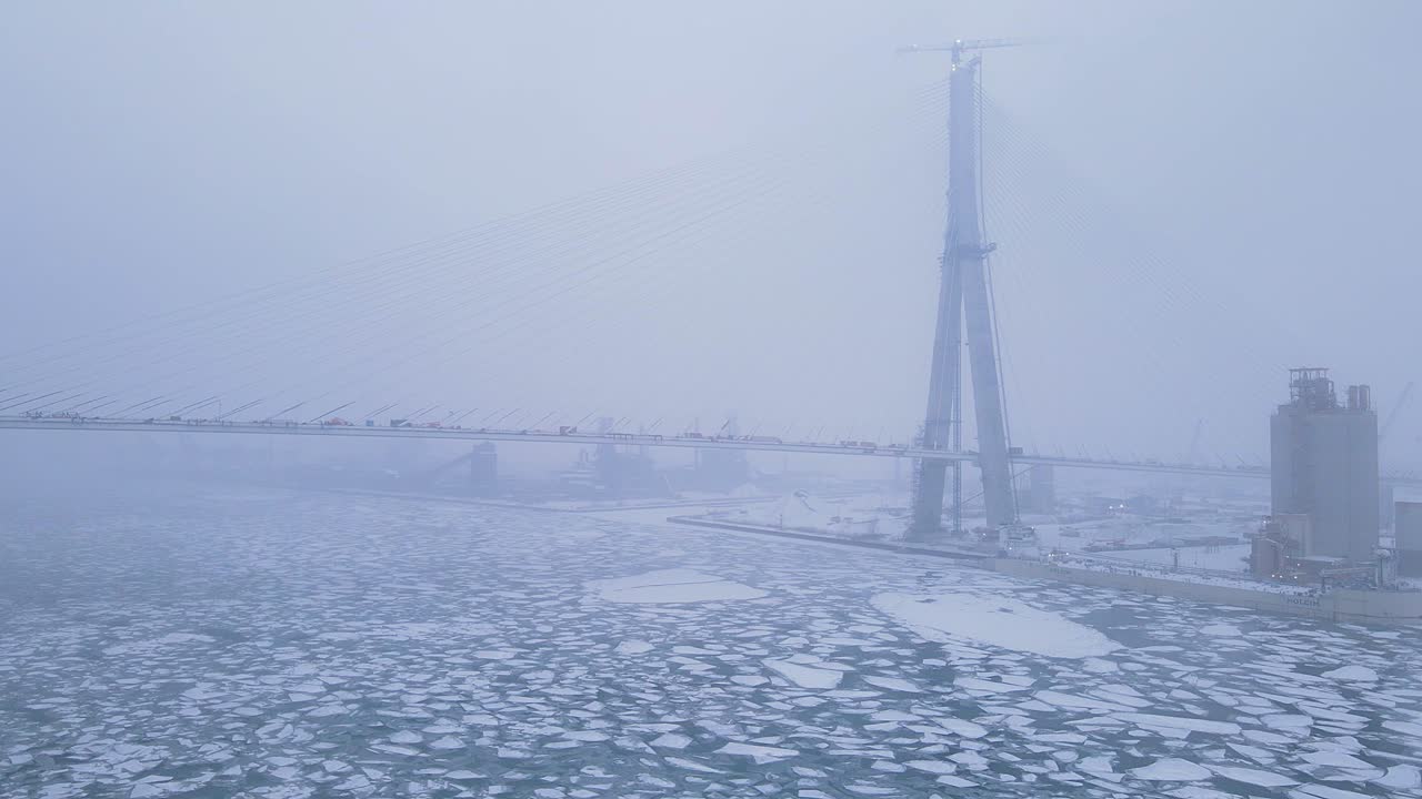 Gordie Howe Bridge vanishes into fog above icy Detroit River on cold winter day