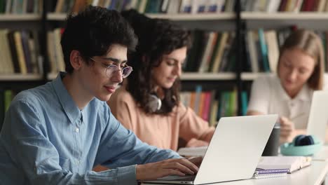 student guy sit at table preparing for exams using laptop