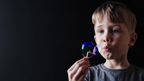 young boy blowing soap bubbles