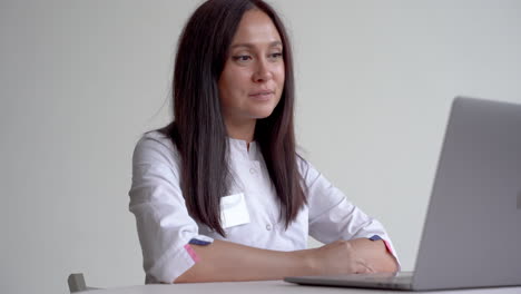 female doctor having a video call and working with a laptop