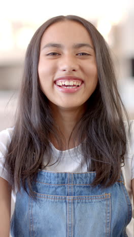 vertical video: smiling teenage girl wearing denim overalls, enjoying time with friends