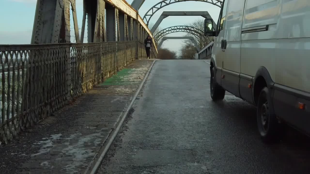 Slow motion motorist van overtaking cyclist POV on bridge