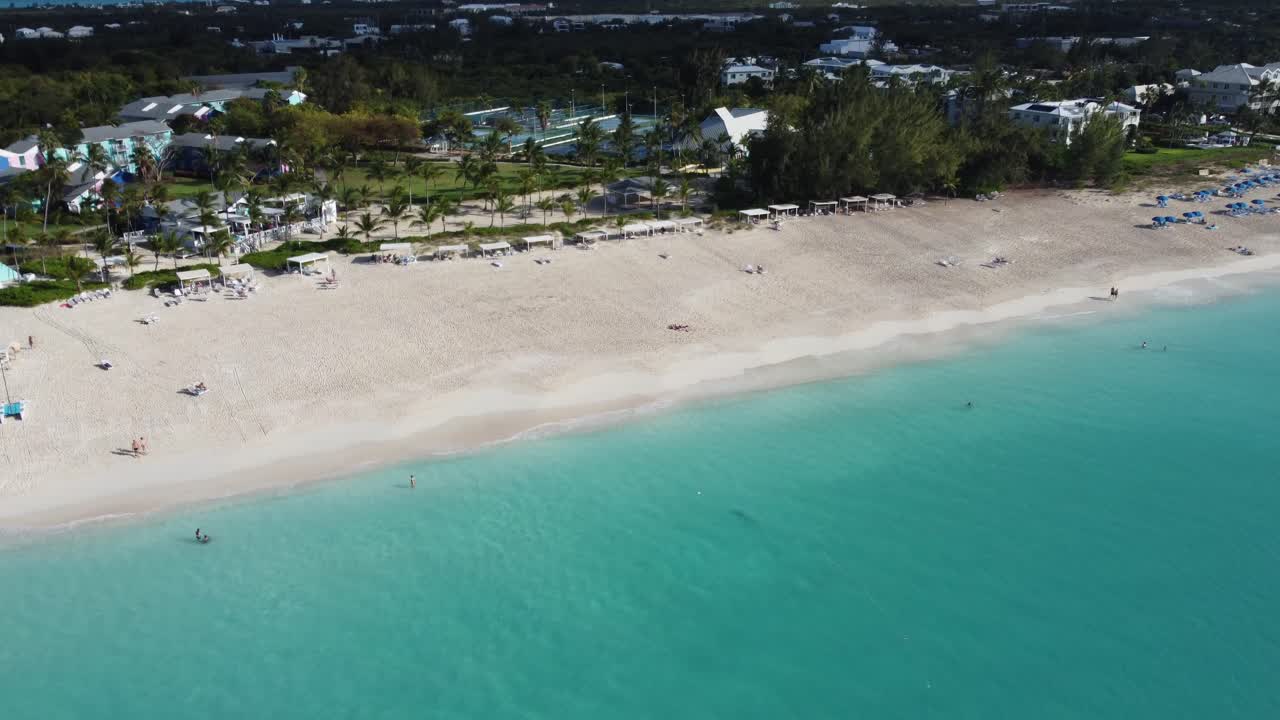 Ripresa aerea dall'alto che cattura un resort sulla spiaggia tropicale caraibica, circondato da acque oceaniche turchesi e una suggestiva costa di sabbia bianca