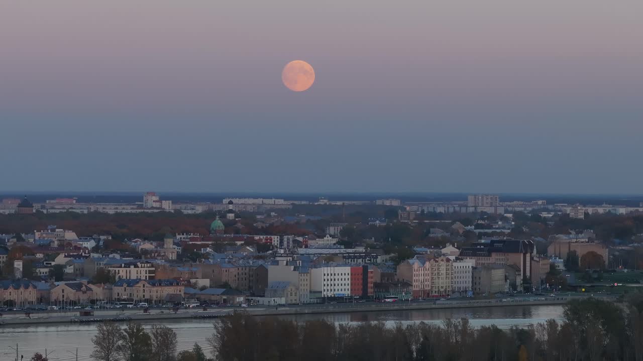 Tele drone shot of sunset with full moon rising over the city skyline - 4K.