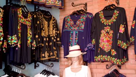 Camera-pans-left-showing-black-and-colorful-huipil-blouses-in-Merida,-Mexico