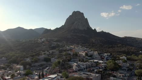 Aerial-View-Of-The-Pena-de-Bernal-Monolith-In-Colonial-Village-Of-Bernal,-Queretaro,-Mexico---drone-pullback