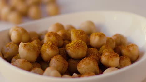 turmeric rain falls in slow motion on chickpeas placed in a white bowl