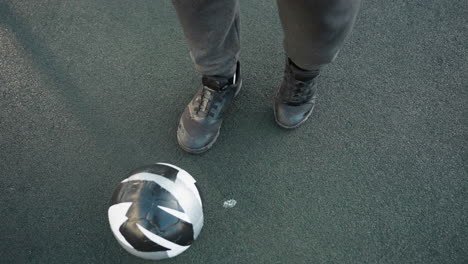 overhead view of athlete demonstrating precise left ankle movements with soccer ball on ground, on textured sports surface in outdoor setting