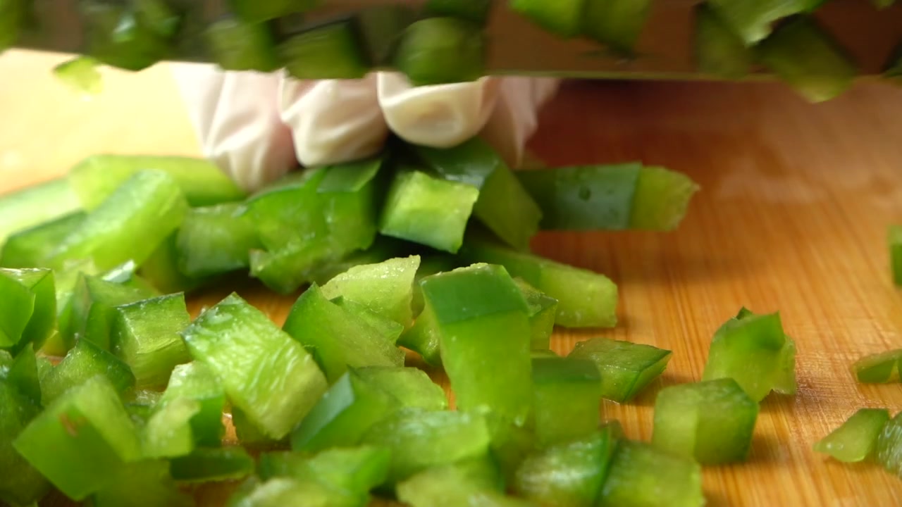 Il cuoco taglia un peperone dolce verde con un coltello. Rallentatore.