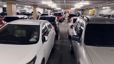garaje de estacionamiento subterráneo con coches y señal de sos