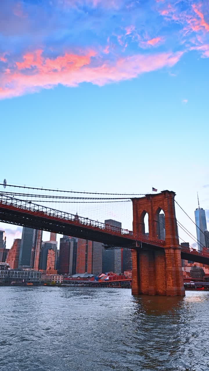Ponte di Brooklyn al tramonto. Il ponte di Brooklyn attraversa l'East River mentre il sole tramonta, proiettando colori vivaci sullo skyline di New York
