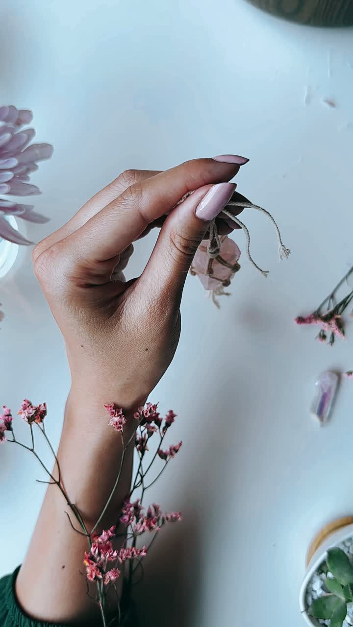 mujer sosteniendo un pendiente de cristal de cuarzo rosa con un cordón de yute natural