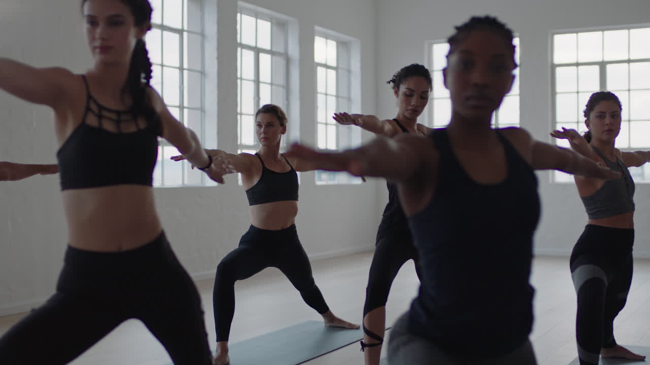 yoga class group of multiracial women practicing warrior pose enjoying healthy lifestyle exercising in fitness studio instructor teaching group meditation at sunrise