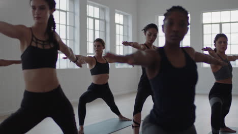 Clase-De-Yoga-Grupo-De-Mujeres-Multirraciales-Practicando-Pose-Guerrera-Disfrutando-De-Un-Estilo-De-Vida-Saludable-Haciendo-Ejercicio-En-El-Gimnasio-Instructor-Enseñando-Meditación-Grupal-Al-Amanecer