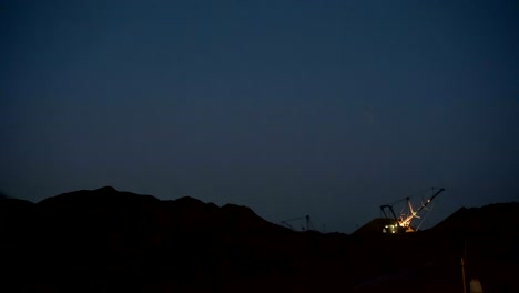 time lapse of excavators loading ore into dump-trucks at the sunset.
