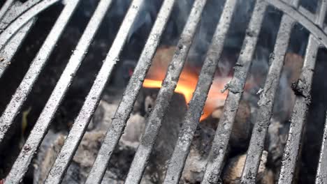 las barras de parrilla al aire libre muestran un primer plano de las llamas y el humo del carbón de leña