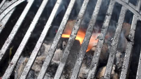 outdoor grill bars closeup showing flames and smoke from buring charcoal