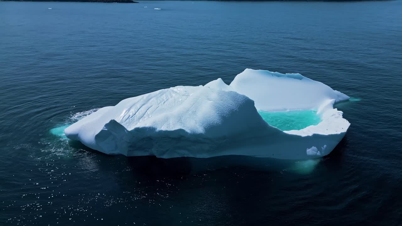 Aerial footage of a large iceberg off Flatrock, Newfoundland, featuring vivid turquoise meltwater in calm Atlantic waters.