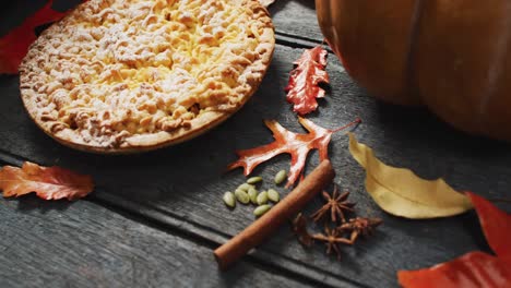 video of autumn leaves, pumpkin, spices and pie on wooden background