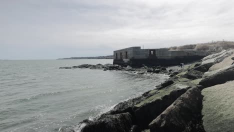 old war time bunker and ocean lookout on the rocky shores of the atlantic ocean in portland maine during a overcast day in 4k