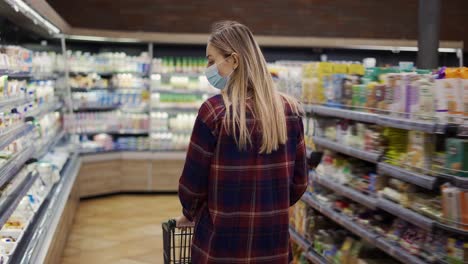 mujer rubia lleva un carro en el supermercado durante el período de cuarentena