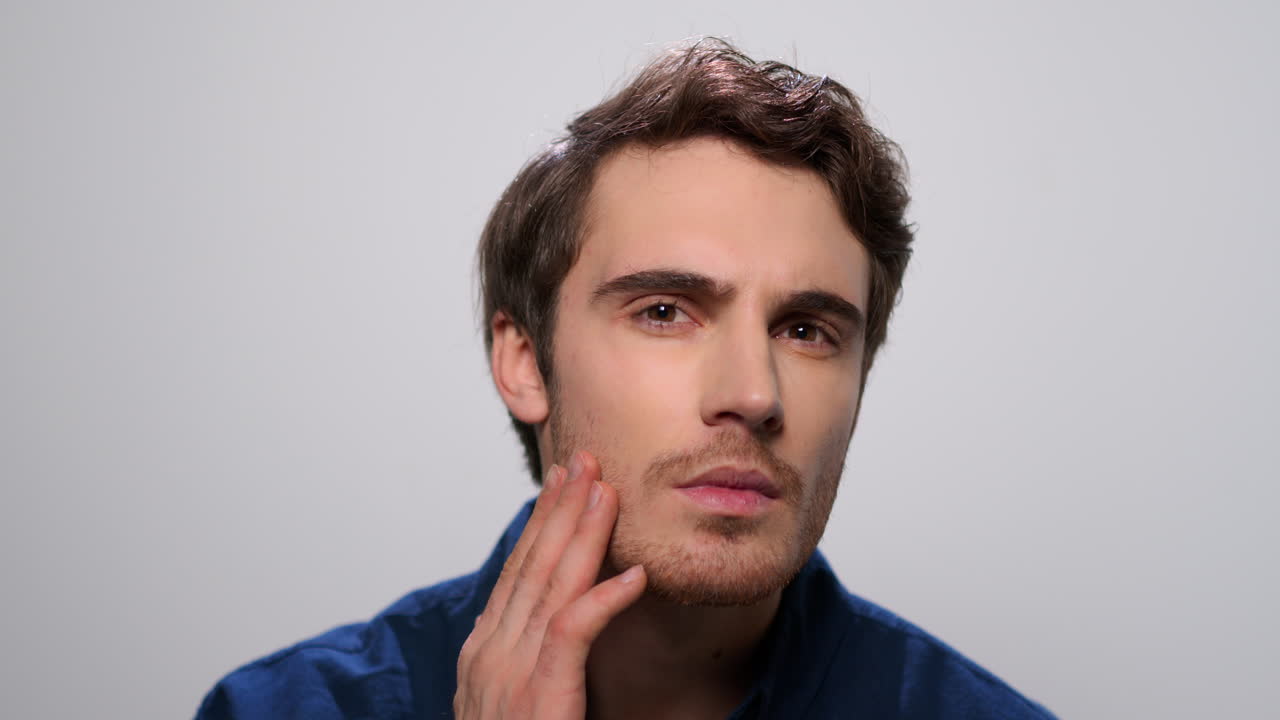 hombre comprobando la barba en el estudio. hombre barbudo tocando la cara con la mano