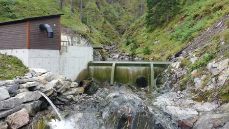 pequeña represa y entrada de la central eléctrica para la pequeña planta hidroeléctrica basada en el río markaani en vaksdal noruega - acercándose a la pequeña represa de entrada y volando sobre ella muy cerca de la superficie del agua