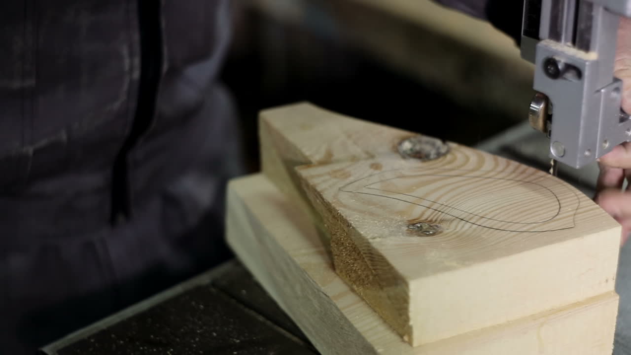 Man Uses An Electric Saw To Cut Wooden Planks. Carpenter is sawing a wooden plank with jig saw machine in carpentry workshop
