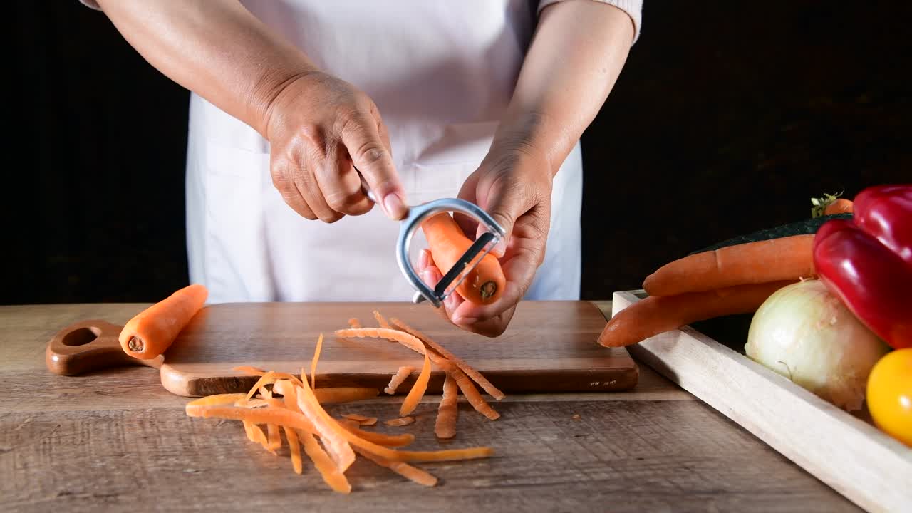 las manos de la mujer pelan zanahorias frescas
