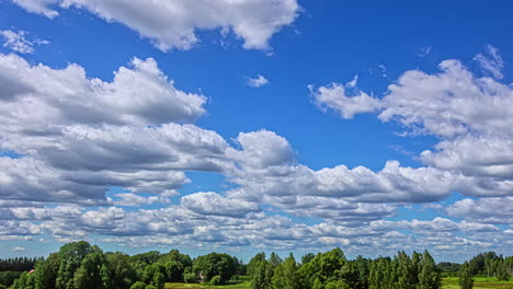 Puffy-cumulus-clouds-float-in-blue-sky,-tree-covered-landscape