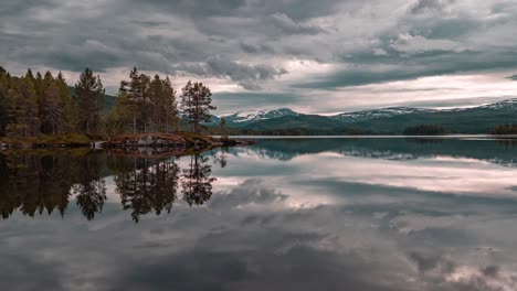 Rosagraue,-Sich-Schnell-Bewegende-Wolken,-Beleuchtet-Von-Der-Untergehenden-Sonne,-Die-Sich-Im-Ruhigen,-Spiegelglatten-Wasser-Des-Sees-Widerspiegeln