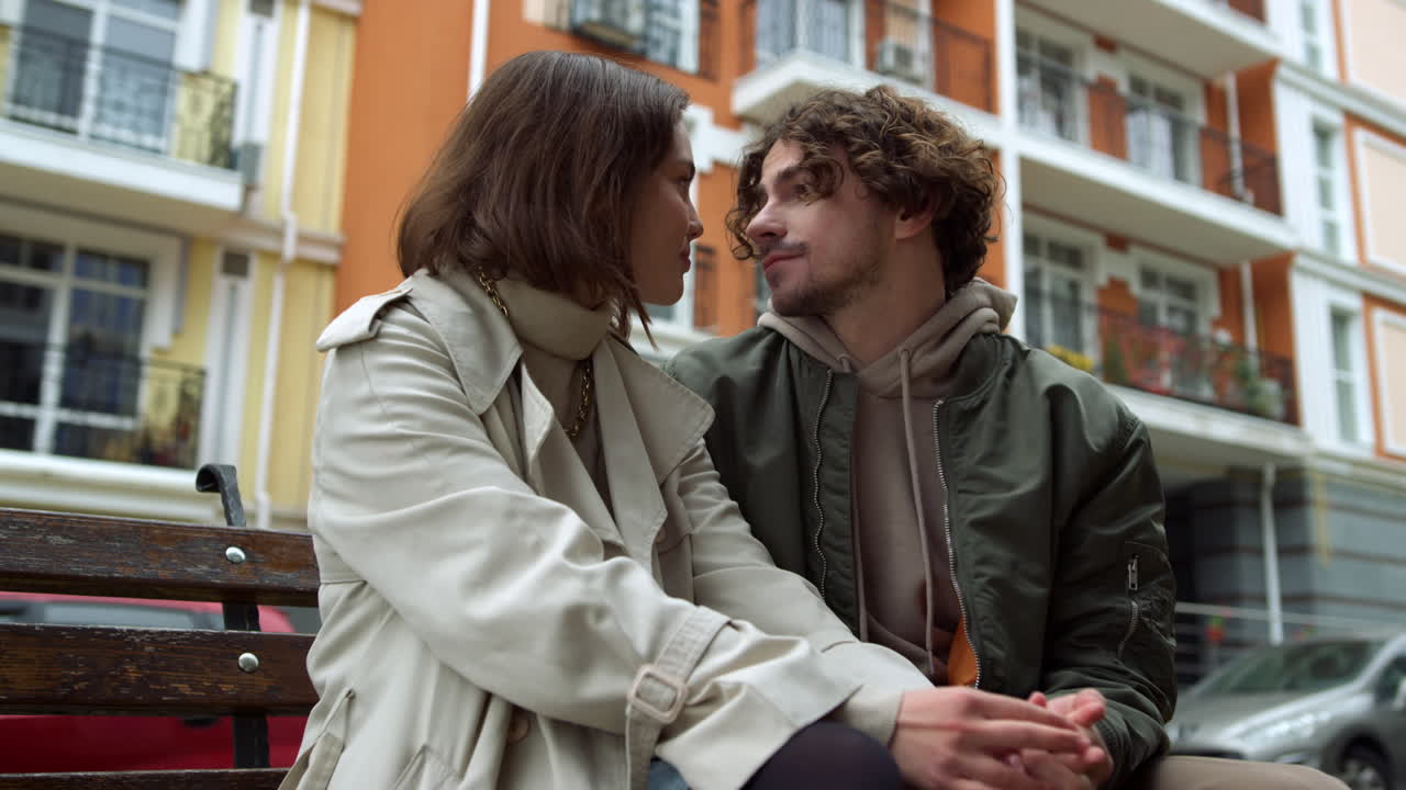 Coppia affettuosa che si bacia su una panchina. Coppia romantica che si guarda negli occhi in città.