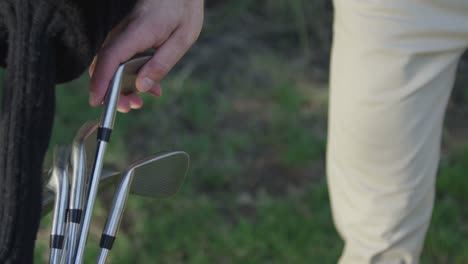 closeup of a golfer pulling a club from his bag